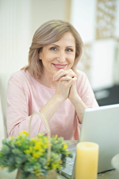 smiling-middle-aged-woman-sitting-table (1)